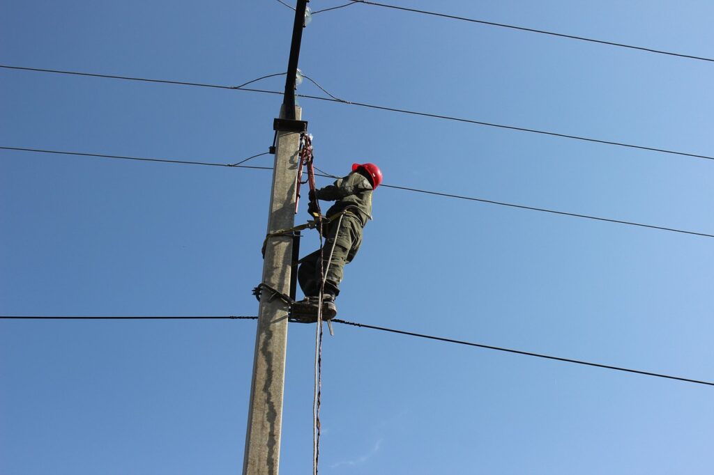 An electric worker checks and repairs utility pole